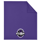 A purple blanket with a folded top-right corner, featuring a 'Celebration Storm' shield logo printed near the bottom center. The logo contains a purple storm cloud graphic with white and black text.